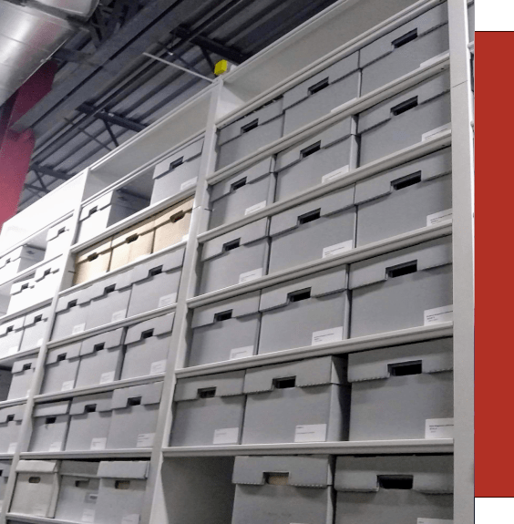 Tall row of shelving with archival boxes containing artifacts in a museum collections area. 