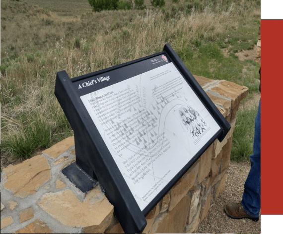 Metal outdoor interpretation panel attached to a rock wall.  